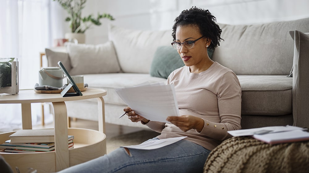 a woman sitting on the floor going over her bills and finances.