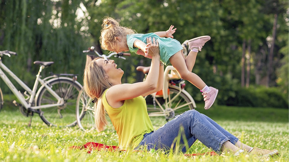 A mom playing with her daughter outside.