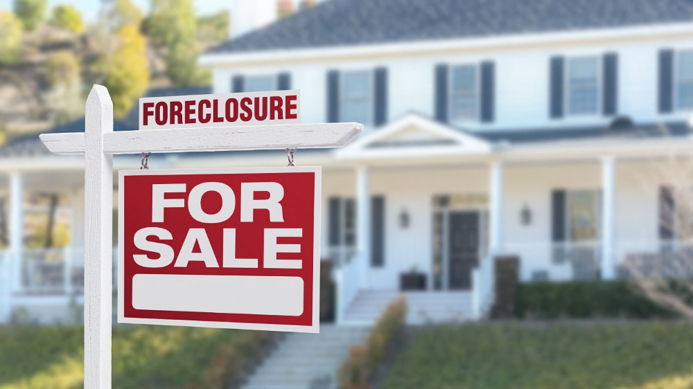 A foreclosure "For Sale" sign in front of a home.