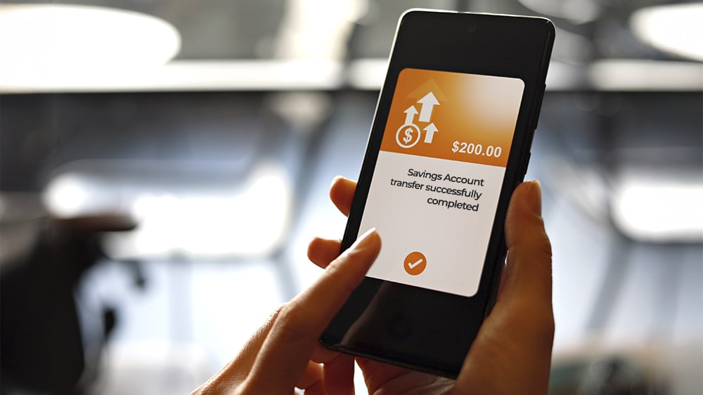 A phone screen showing the amount in a savings account increased.